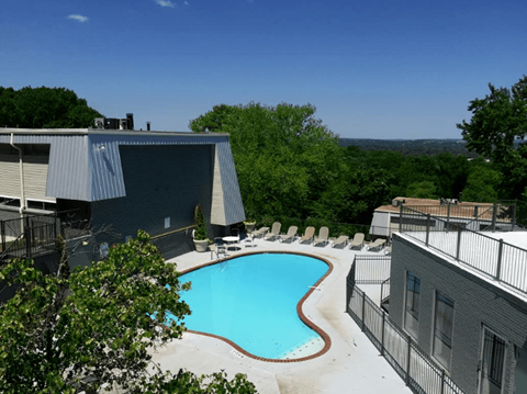 A swimming pool surrounded by trees and buildings.