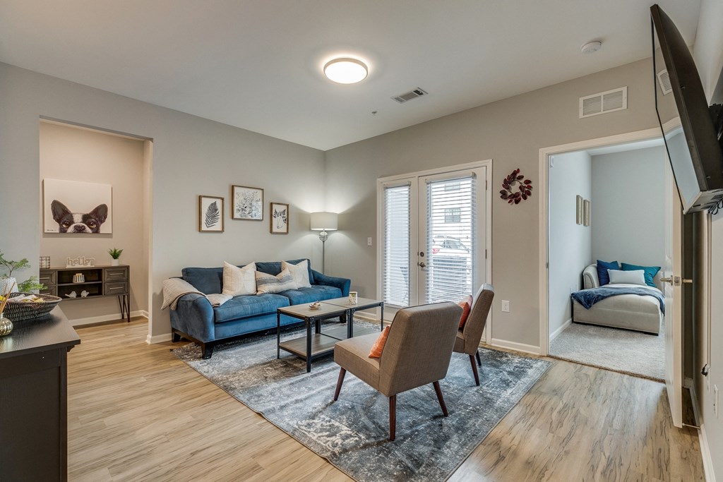 an open living room with a couch and chairs and a door to a bedroom
