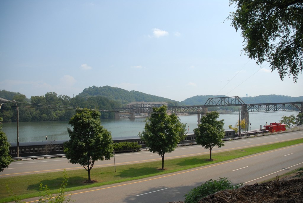 a train crossing a bridge over a river next to a highway