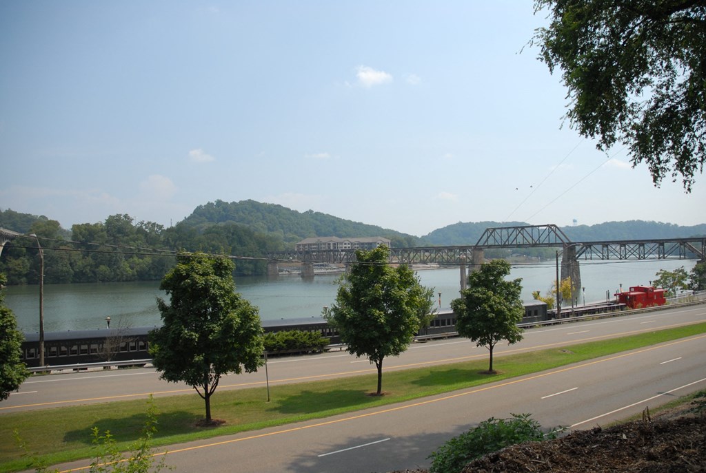 a train crossing a bridge over a river next to a highway