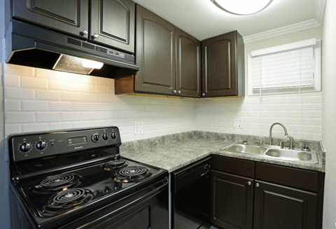 A kitchen with a black stove and brown cabinets.