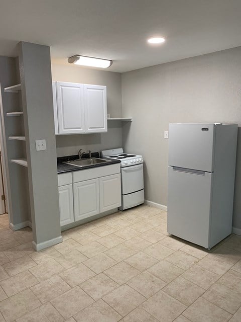a kitchen with white cabinets and a refrigerator and a sink