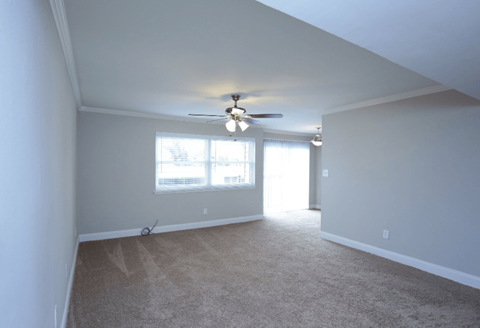 A room with a ceiling fan and carpeted floor.