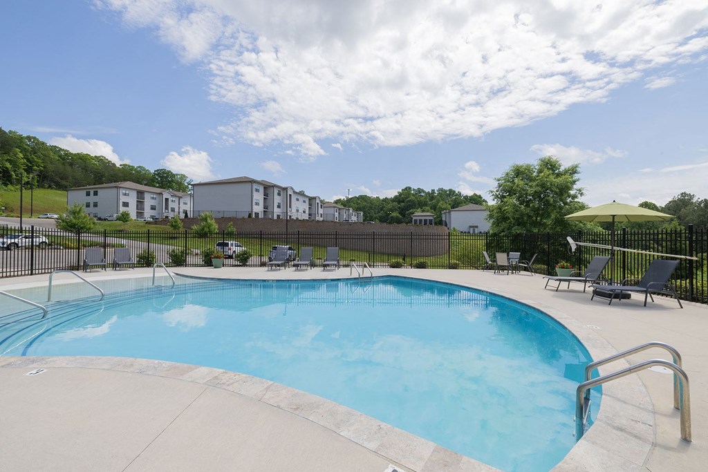 a swimming pool with chairs and a fence around it