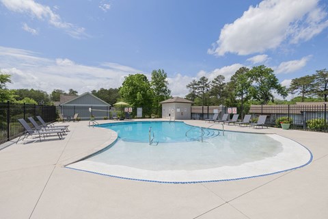 our apartments have an outdoor pool with chairs and trees