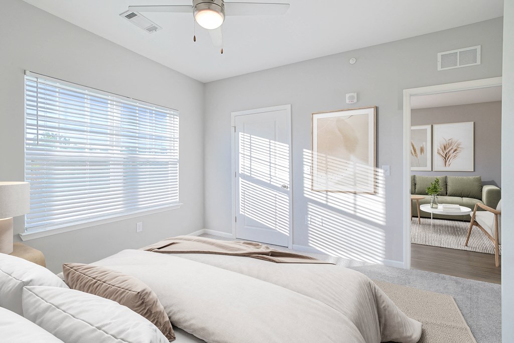 A bedroom with a large bed and a window with blinds.