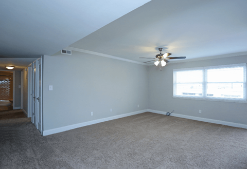A room with a ceiling fan and a window with blinds.