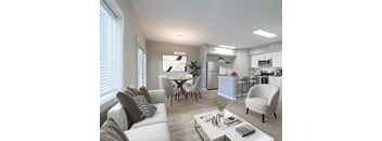 A modern living room with a grey sofa, a white coffee table, and a kitchen in the background.