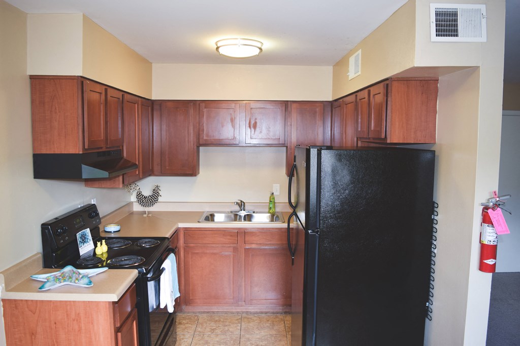 a kitchen with wooden cabinets and a black refrigerator