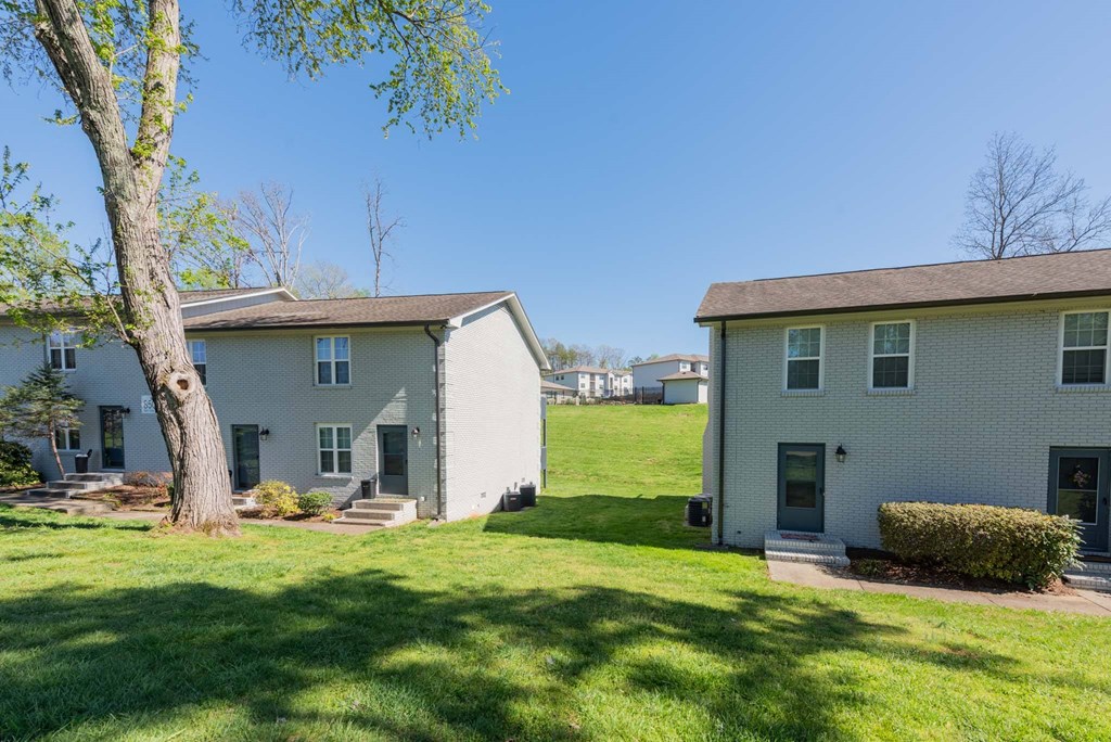 a view of two houses with a lawn and a tree