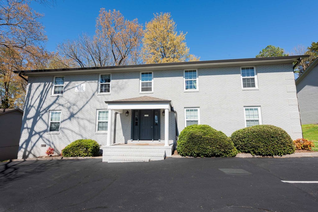 the front of a white house with a black door