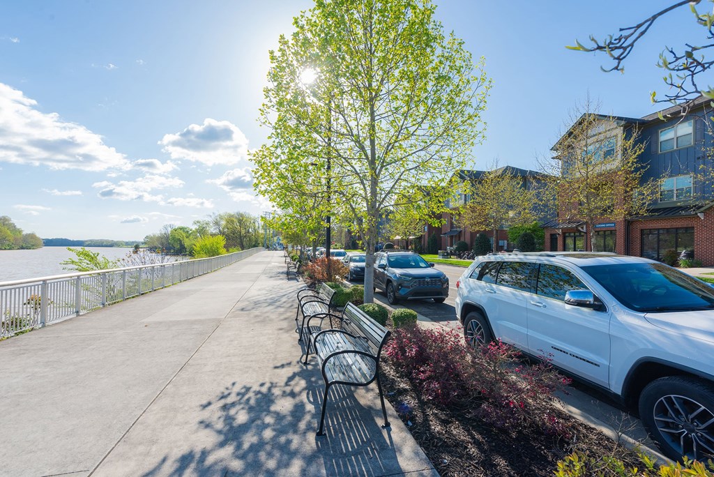 a row of cars parked on a sidewalk next to a river