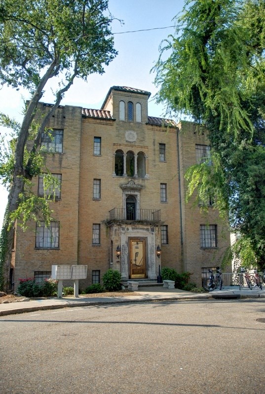 a large brick building with a door and a tree