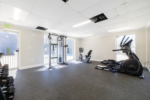 A spacious gym with a variety of equipment including treadmills, stationary bikes, and a weight machine.