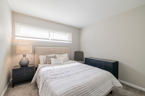 A bedroom with a bed, nightstand, and window.
