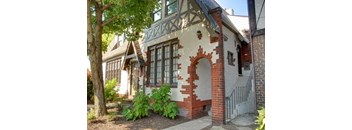 the front of a brick house with a door and a tree