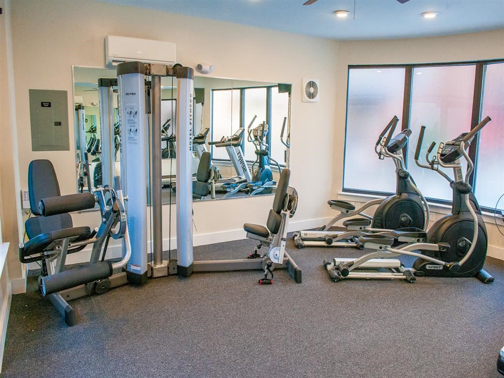 a gym with cardio machines and weights on the floor