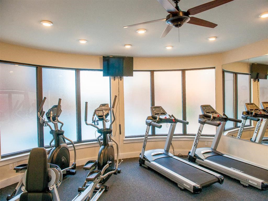 a gym with several machines and a ceiling fan
