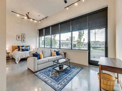 a living room with a bed and a couch in front of a window