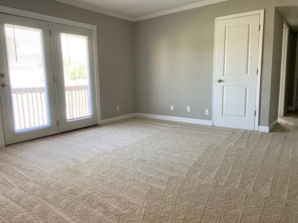 an empty room with a door and a carpeted floor