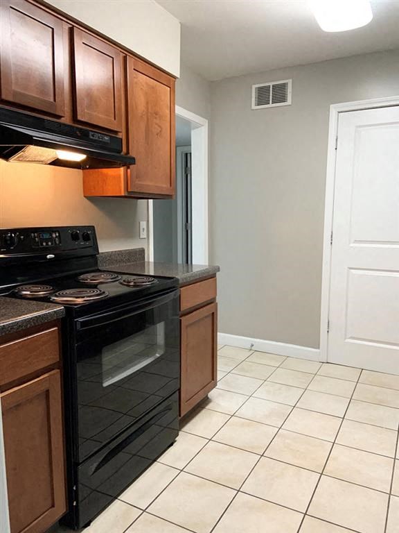 a kitchen with a black stove and a white tiled floor