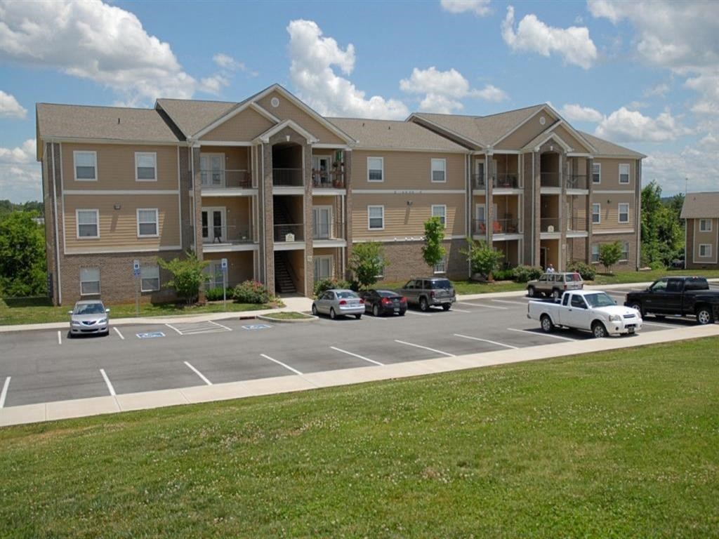 an apartment building with cars parked in a parking lot