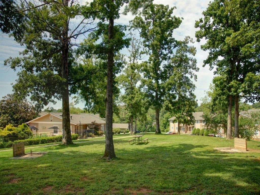 a park with trees and houses in the background