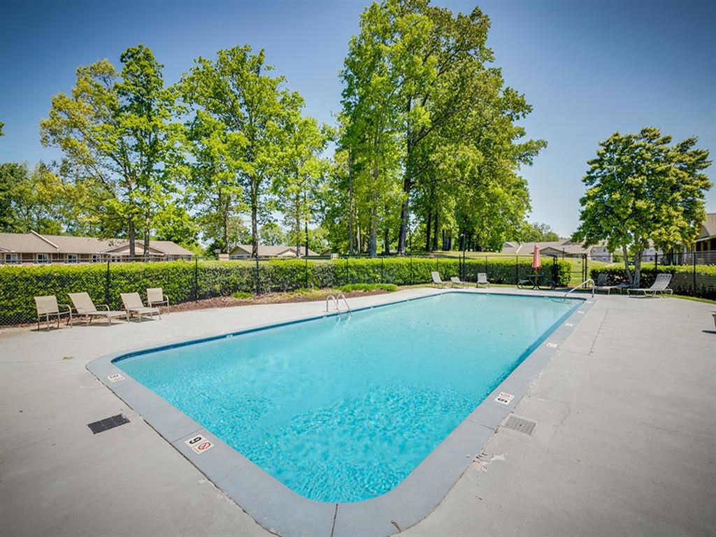 a swimming pool with trees and chairs around it