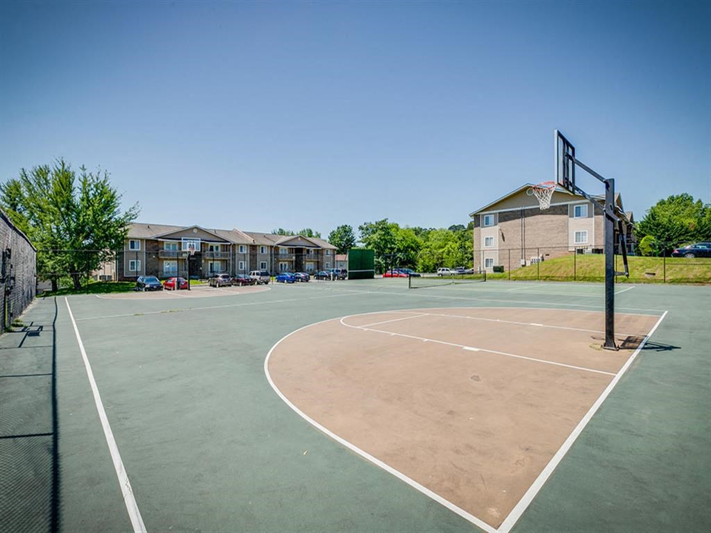an empty basketball court with apartments in the background