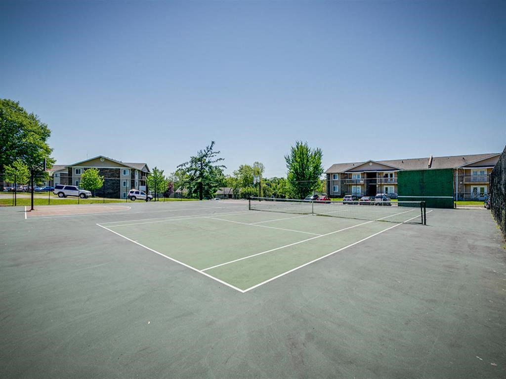 a tennis court with buildings in the background
