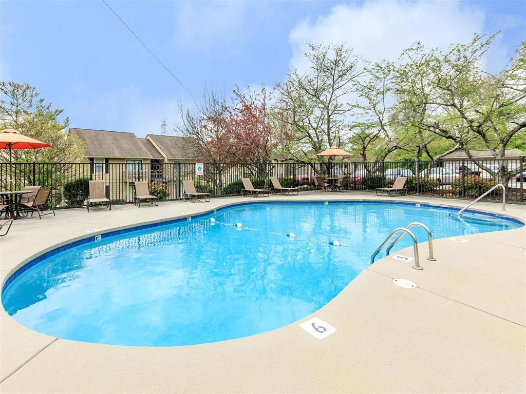 a resort style swimming pool with chairs and umbrellas