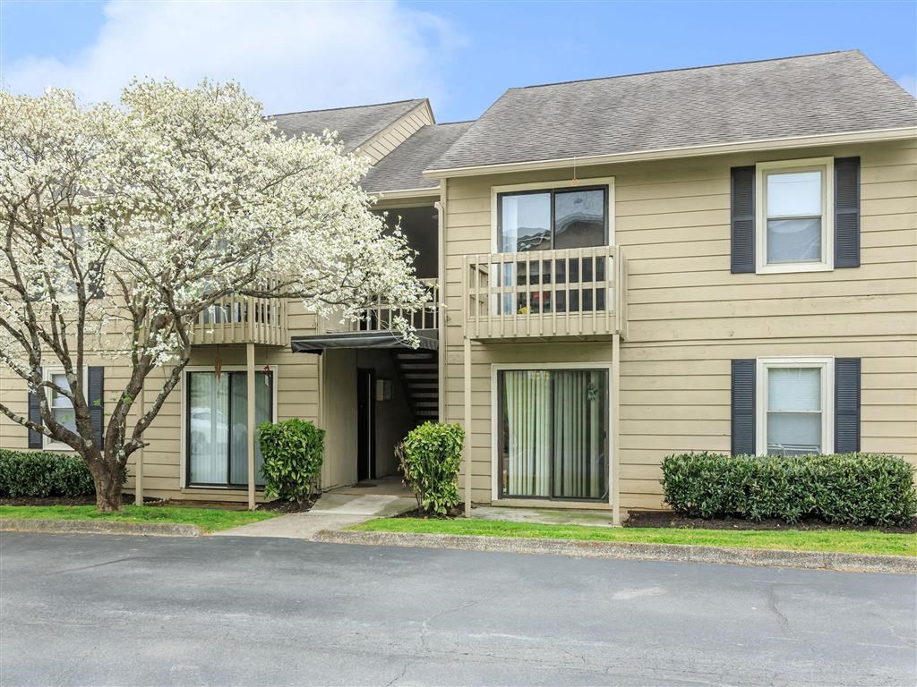 a beige house with a balcony and a tree in front of it