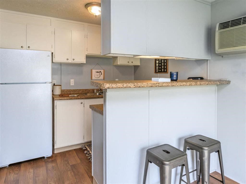 a kitchen with a bar and stools and a refrigerator