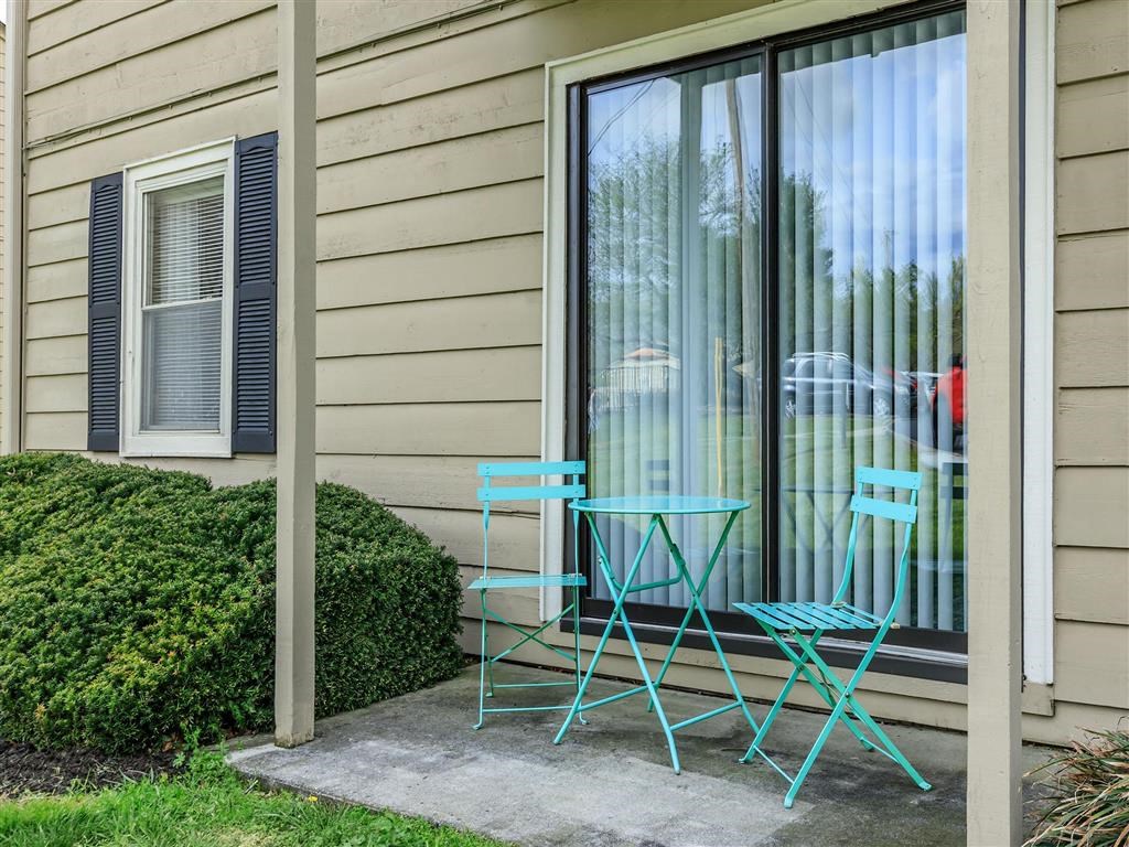 a patio with two blue chairs and a table on a patio