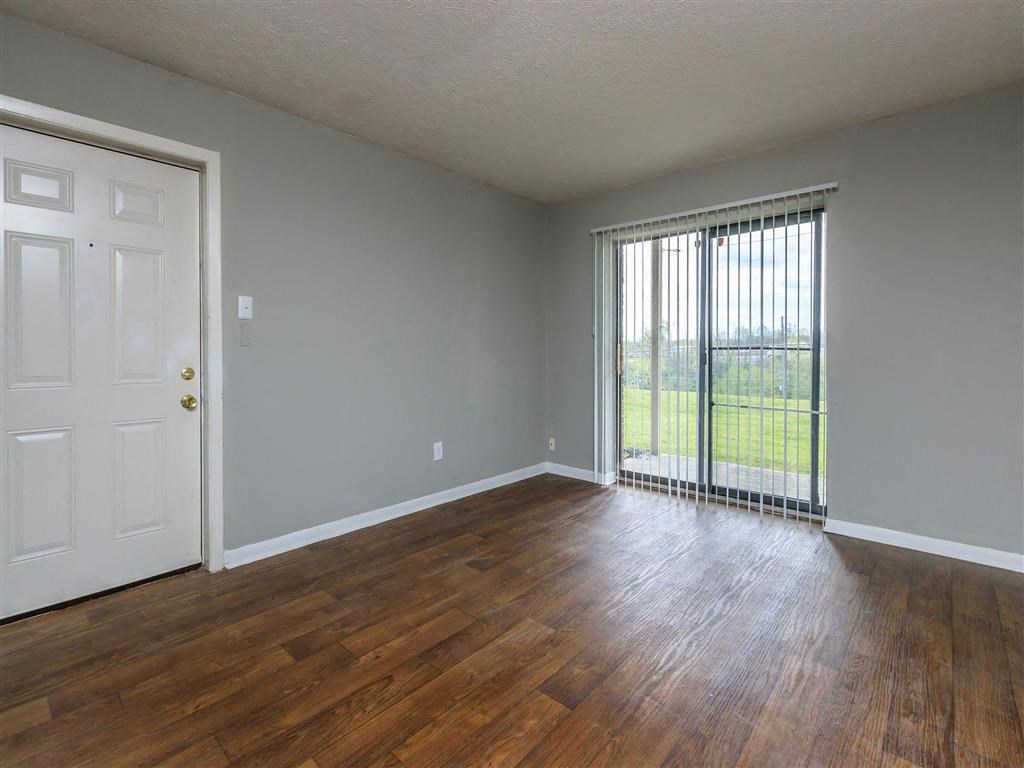 an empty living room with wood floors and a window
