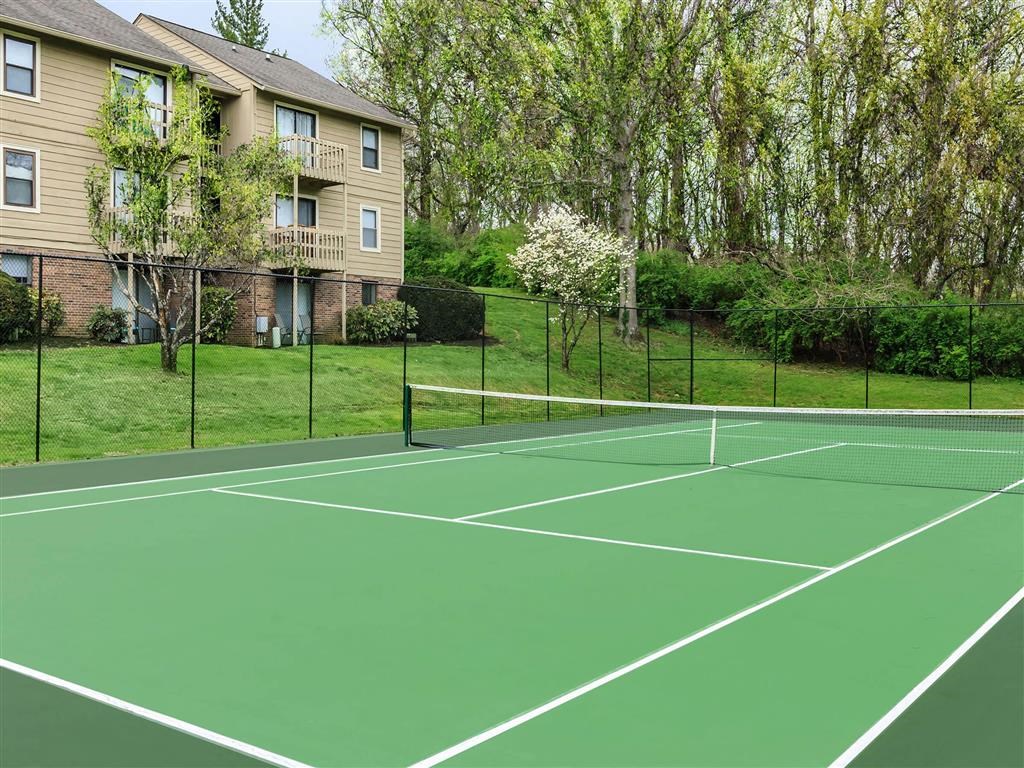 a tennis court with a house in the background