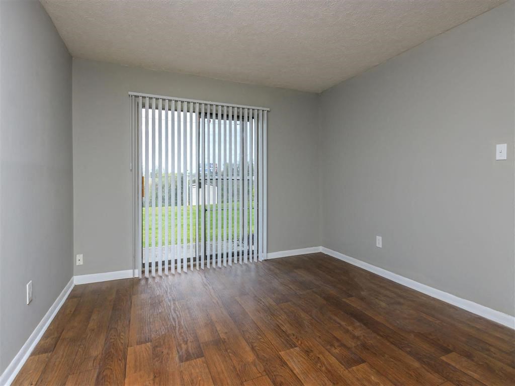 an empty living room with wood floors and a sliding glass door