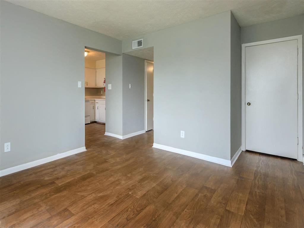 the living room and kitchen of an empty house with a wooden floor