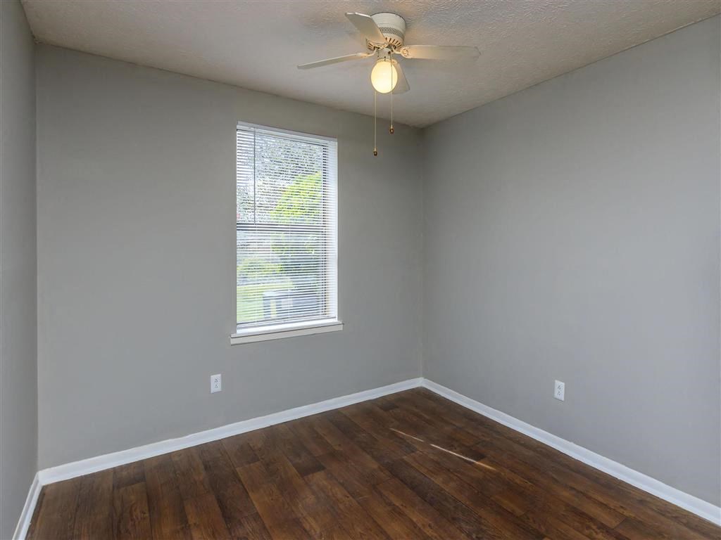 an empty room with a ceiling fan and a window