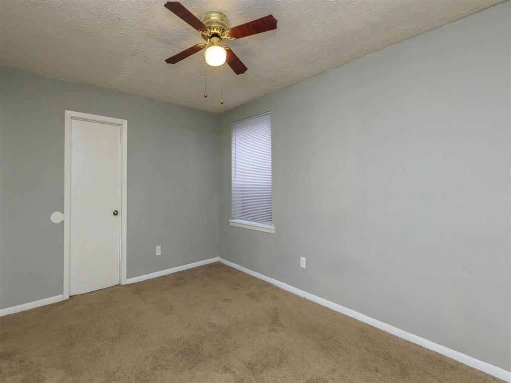 an empty room with a ceiling fan and a door