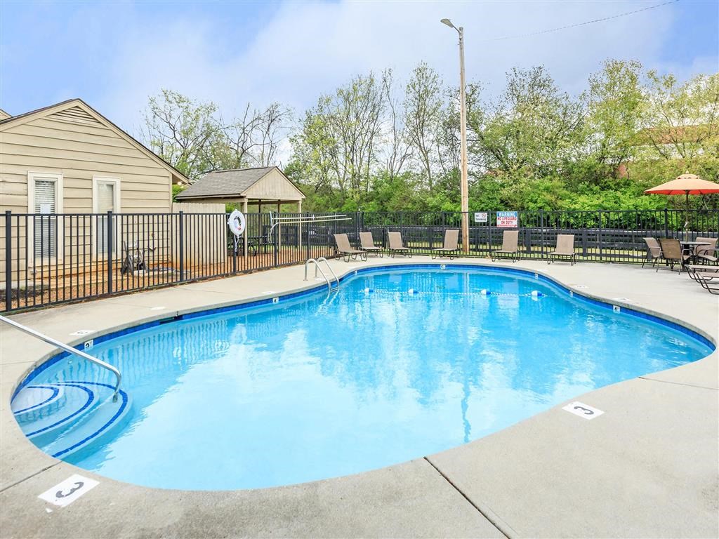 a resort style pool with chairs and a fence around it