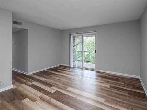 A room with wooden flooring and a sliding glass door.