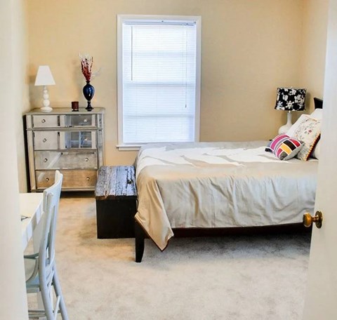 A bedroom with a bed, nightstand, and chair.