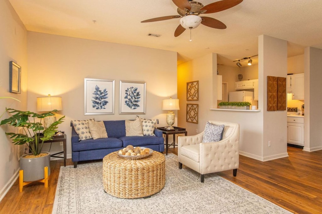 A living room with a blue couch, a white chair, and a wicker table.