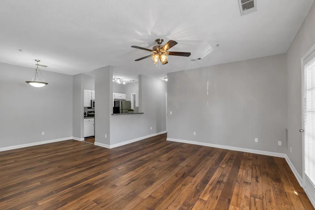 A room with a ceiling fan and wooden flooring.