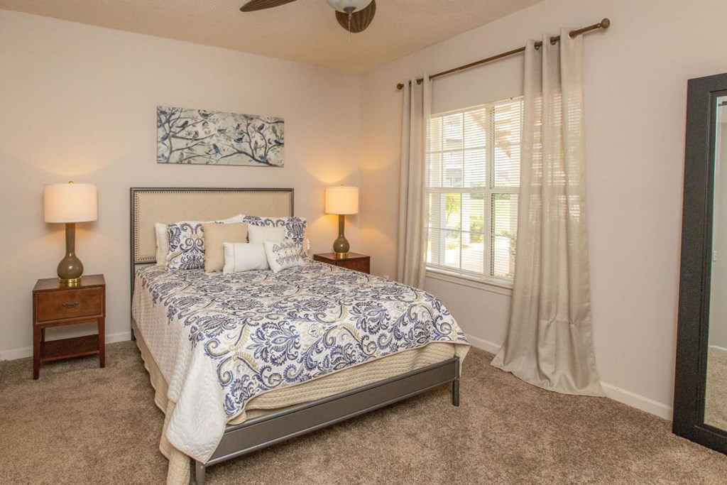 A bedroom with a bed, two lamps, and a painting on the wall.