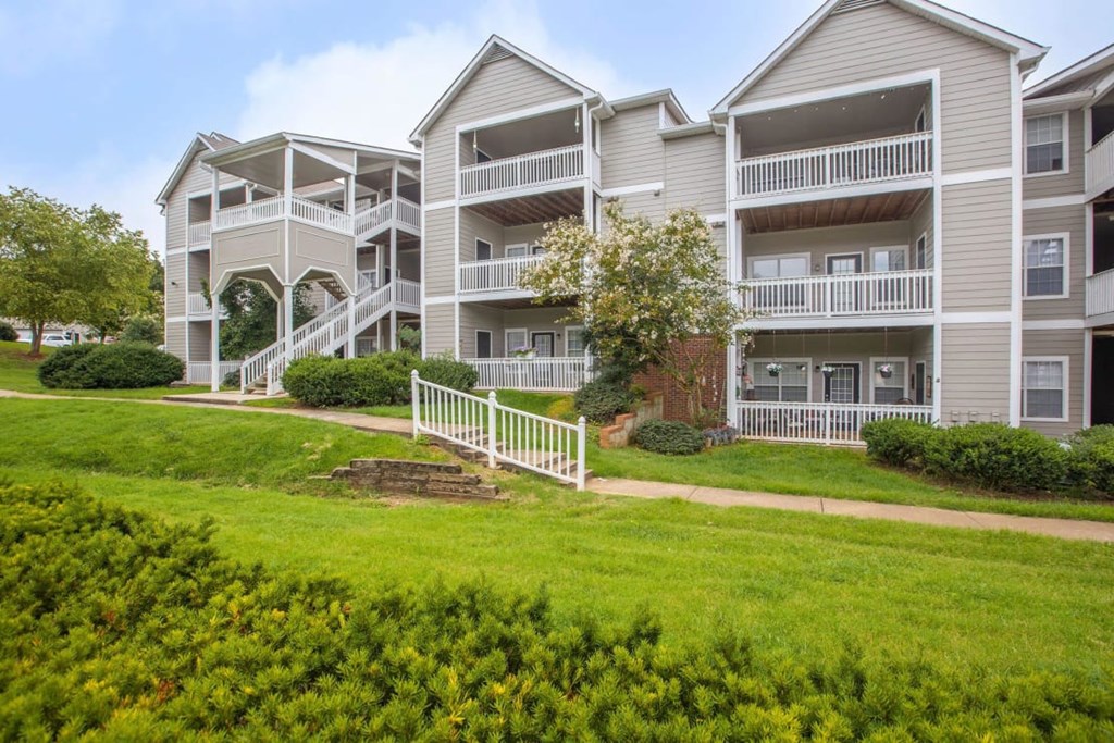 Apartment complex with green grass and white fence.
