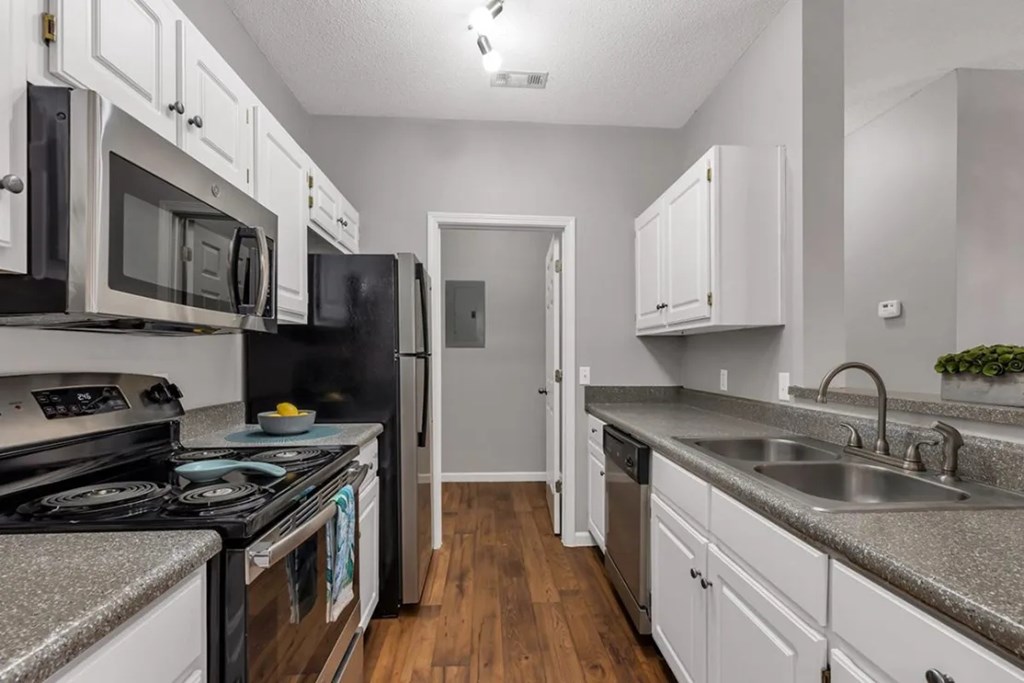 A kitchen with black appliances and white cabinets.