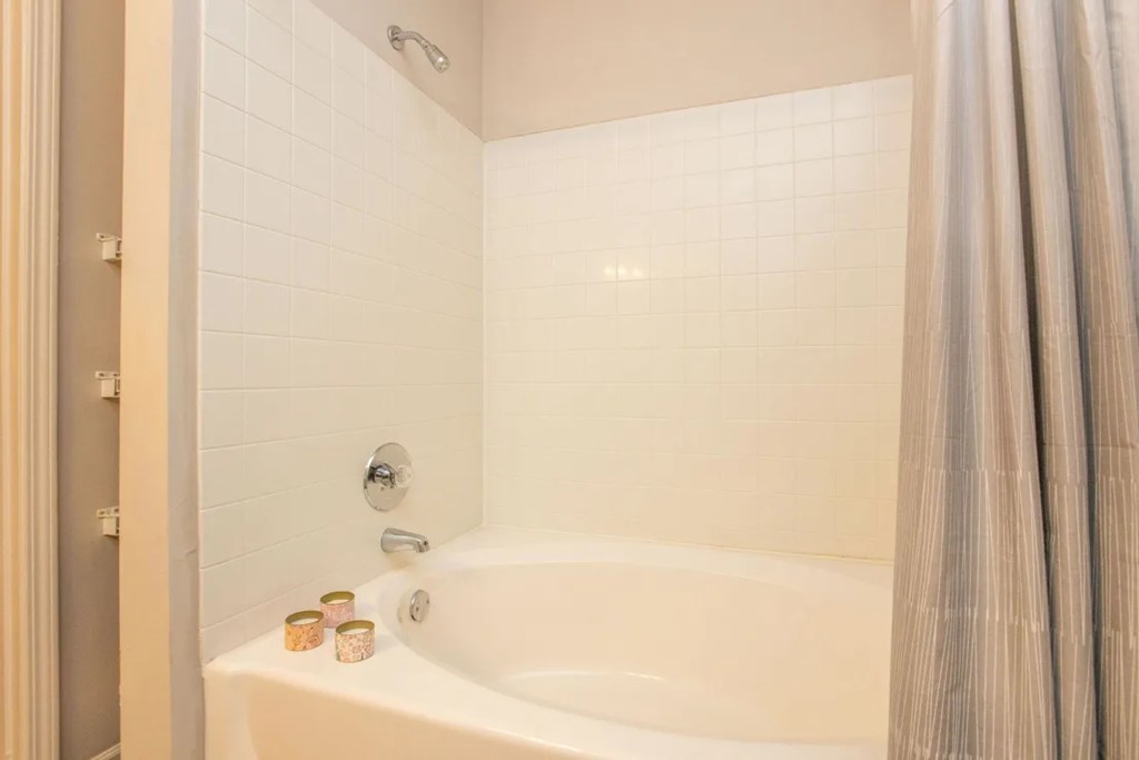 A white bathtub with a shower curtain and a shower head.