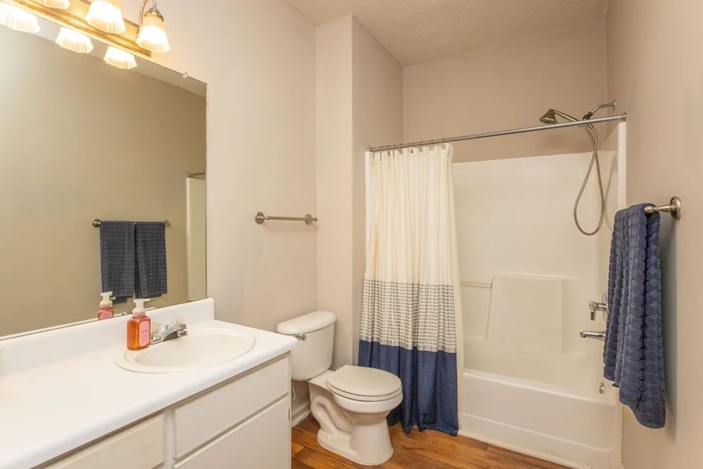 A white bathroom with a toilet, sink, and shower.